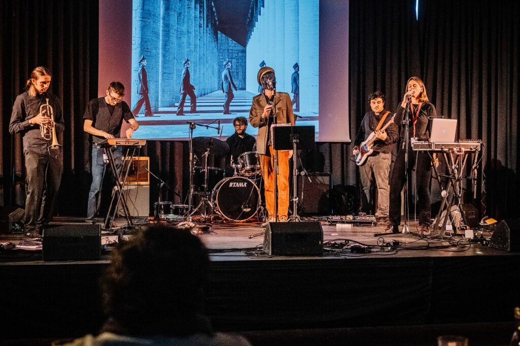 Libellule accompagnato da dei musicisti mentre suonano Nuovo Ordine