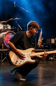 Xesse in ginocchio sul palco con la chitarra